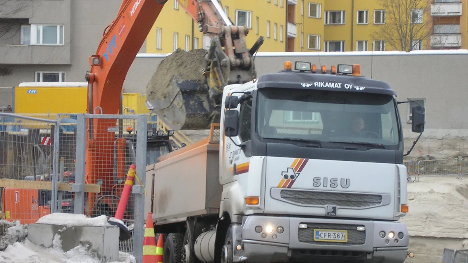 Excavator loading sand into a dump truck at a site
